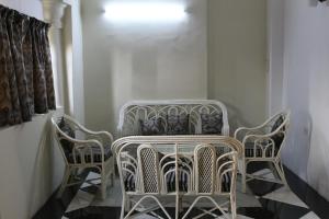 eine Gruppe von Stühlen und einem Tisch in einem Zimmer in der Unterkunft Chowdhury's Guest House in Kalkutta