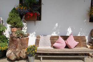 eine Holzbank mit vier Kissen darauf mit Pflanzen in der Unterkunft Stillinghof in Saalfelden am Steinernen Meer