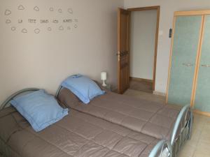 een bed met twee blauwe kussens in een kamer bij Gite de la Boheraie in Chemazé
