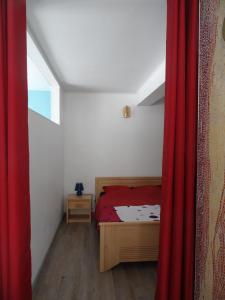 a bedroom with a bed and a red curtain at Gîte du héron in La Wantzenau