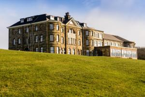 un grand bâtiment au sommet d'une colline herbeuse dans l'établissement Grand Villa Heights, à Ravenscar