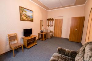 a living room with a couch and a television at Tri Peskarya Hotel in Kursk