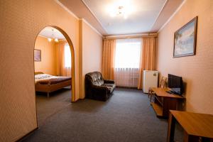 een hotelkamer met een spiegel, een stoel en een bed bij Tri Peskarya Hotel in Koersk