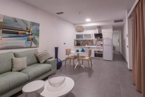a living room with a couch and tables and a kitchen at Aevum Resort in Playa del Ingles