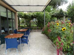 a patio with tables and chairs and a garden with sunflowers at Quinta das Delicias in São Tiaguinho