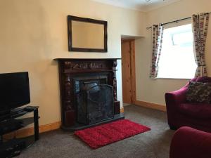 a living room with a fireplace and a red rug at High Road Cottage in Achill