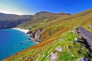 a road on a hill next to the ocean at High Road Cottage in Achill