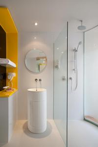 a white bathroom with a sink and a shower at KIMAYA Braga Bandung by HARRIS in Bandung