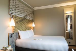 Schlafzimmer mit einem weißen Bett mit Kopfteil in der Unterkunft ibis Genève Aéroport in Genf