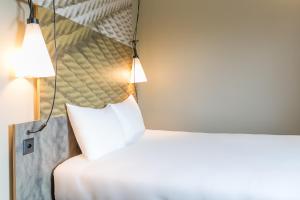 - une chambre avec un lit blanc et un miroir dans l'établissement ibis Genève Aéroport, à Genève