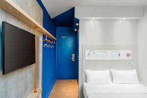 a room with a blue accent wall and a tv at Ibis Budget Amiens Centre Gare in Amiens