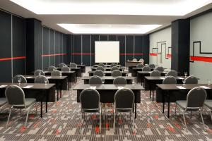 a conference room with tables and chairs and a whiteboard at KIMAYA Braga Bandung by HARRIS in Bandung