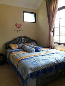a bedroom with a bed with pillows and a window at Villa Kota Bunga NA2 in Puncak