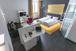 a bedroom with a bed and a desk with a laptop at Hotel Sinsheim in Sinsheim