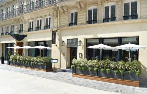 a building with umbrellas and plants in front of it at Maison Albar Hotels Le Pont-Neuf in Paris