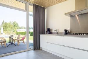 uma cozinha com armários brancos e uma mesa com cadeiras em Luxe Tiny House em Stroe