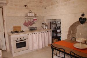 een keuken met een wit fornuis en een tafel met een tafelblad bij il trullo di giada e mattia in Alberobello +50 foto's
