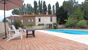 - une terrasse avec une table et un parasol à côté de la piscine dans l'établissement Chambres d'hôtes La Luciole, à Tourtrol