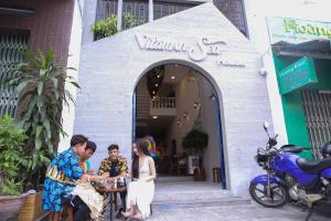 a group of people sitting at a table outside a restaurant at Vitamin Sea Homestay Nha Trang in Nha Trang