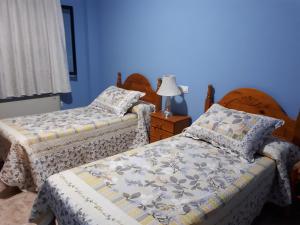 2 camas en una habitación con paredes azules en Hostal Julio, en Trujillo