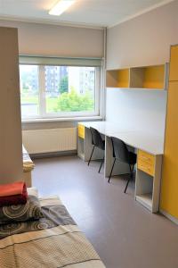 um quarto com uma secretária, cadeiras e uma janela em Downtown Hostel em Tartu