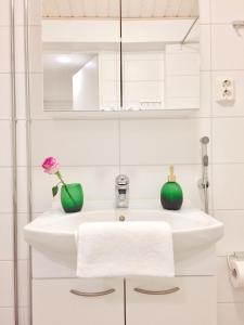 a bathroom with a white sink with two green vases at Lahti Center Design Apartment Uno in Lahti