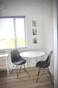2 sillas y una mesa en una habitación con ventana en Lynghagi House en Vegamót