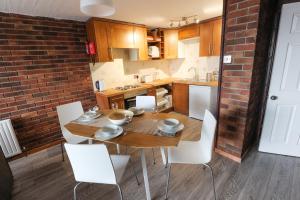 eine Küche mit einem Holztisch und weißen Stühlen in der Unterkunft South Fistral View Apartment in Newquay