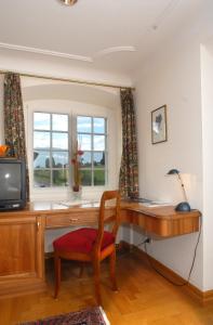 a room with a desk with a television and a chair at Hotel Gasthof Löwen in Vaduz