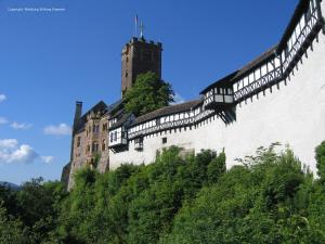 zamek na szczycie wzgórza z drzewami w obiekcie Gästehaus Wohngut Eisenach w mieście Eisenach