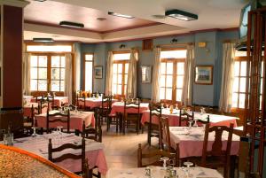 a dining room with tables and chairs and windows at Hotel Menano in Manzanares