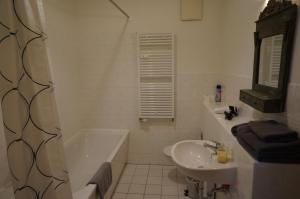 een witte badkamer met een wastafel, een bad en een toilet bij bluming inn - Ferienwohnung im Spreewald in Lübben