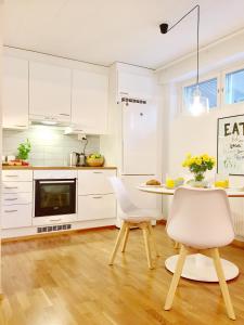 a kitchen with white cabinets and a table and chairs at Lahti Center Design Apartment Uno in Lahti