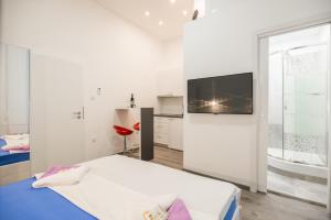 Downtown Rijeka في رييكا: غرفة نوم بيضاء مع سرير وتلفزيون على الحائط