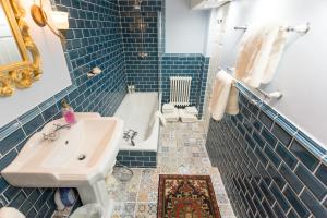 La salle de bains est pourvue de carrelage bleu, d'un lavabo et d'une baignoire. dans l'établissement The Ascott, à Manchester