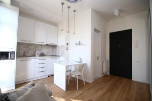 une cuisine avec des placards blancs et une table avec une chaise dans l'établissement Avlabari Apartment, à Tbilissi