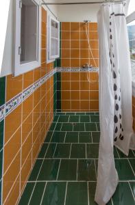 y baño con ducha y azulejos de color naranja y verde. en Fit und Fun Sportherberge, en Kötschach-Mauthen