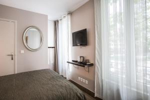 a hotel room with a television and a bed at Le Figuier in Ivry-sur-Seine