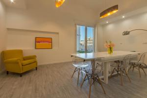 a living room with a dining room table and a yellow chair at Spacebility City - self check-in in Cagliari