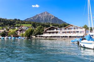 a marina with boats in the water with a mountain at Strandhotel Seeblick in Faulensee