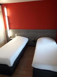 2 camas en una habitación con una pared roja en HOTEL PREMIERE CLASSE Rouen Sud Oissel en Saint-Étienne-du-Rouvray