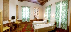 a hotel room with two beds and a tv at Qosha Darvoza in Khiva