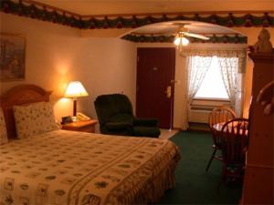 a bedroom with a bed and a chair and a window at Townhouse Inn & Suites Omaha in Omaha