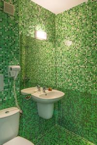 a green tiled bathroom with a sink and a toilet at Hotel Boomerang - Sunny Beach in Sunny Beach