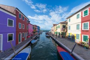 a canal with colorful buildings and boats in the water at Casa Nova in Burano