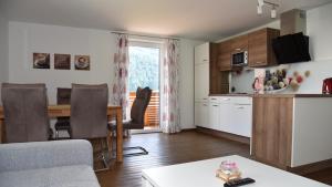 Sunseitn Apartments في غوساو: غرفة معيشة مع مطبخ وطاولة مع كراسي
