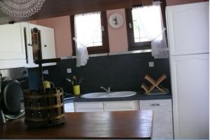 - une cuisine avec un évier et 2 fenêtres dans l'établissement Maison Bord Du Lac, à Marcillac-la-Croisille