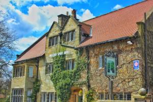 an old stone building with a red roof at Mallyan Spout Hotel in Goathland