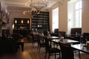 a dining room with tables and chairs and a chandelier at Abdij Hotel Rolduc in Kerkrade