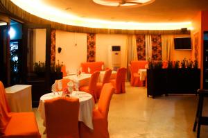 ein Restaurant mit zwei Tischen und orangefarbenen Stühlen und Tischsucher in der Unterkunft Hotel Le Marly in Abidjan